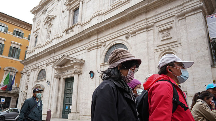 Tourists wearing protective masks walk past the St. Louis of the French church in Rome, Sunday, March 1, 2020. The French community church in Rome, St. Louis of the French, closed its doors to the public on Sunday, reportedly after a priest was infected with a new virus. - AP Photo/Andrew Medichini
