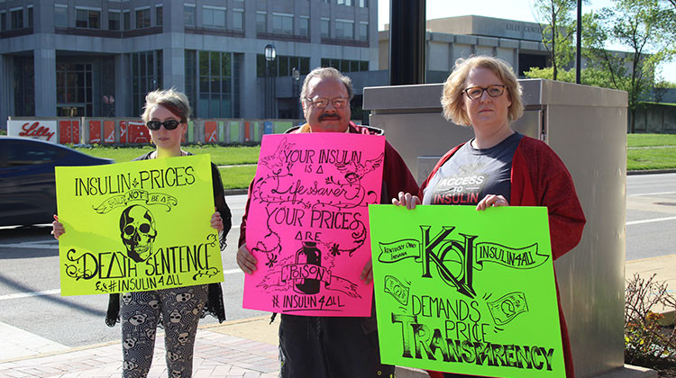 Mackenzie Fields, Dan Meno and Eryn Ruder hold signs on the street across from Eli Lilly prior to the shareholder meeting. Fields illustrated all three of the signs. - Samantha Horton/IPB News