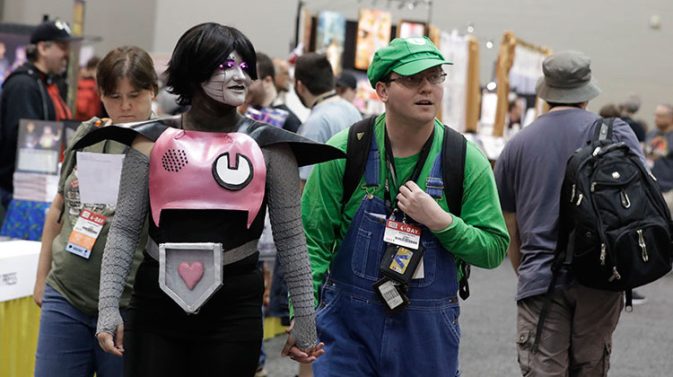 Ember Welden and Brandon Sanders view the displays as they walk through the Indiana Convention Center during Gen Con, Thursday, Aug. 1, 2019, in Indianapolis. The annual convention for consumer fantasy, electronic, sci-fi, adventure and hobby gaming set a new attendance record this year. - AP Photo/Darron Cummings