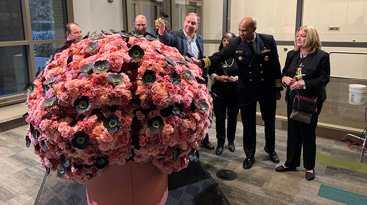 U.S. Surgeon General Dr. Jerome Adams (second from right) pulls a flower from a brain-shaped sculpture meant to symbolize some of those who've died from drug addiction. - Stan Jastrzebski/WBAA