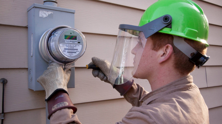An employee of Wellington Energy Inc. works to install a new watthour meter at a residence in Portland, Oregon.  - Portland General Electric