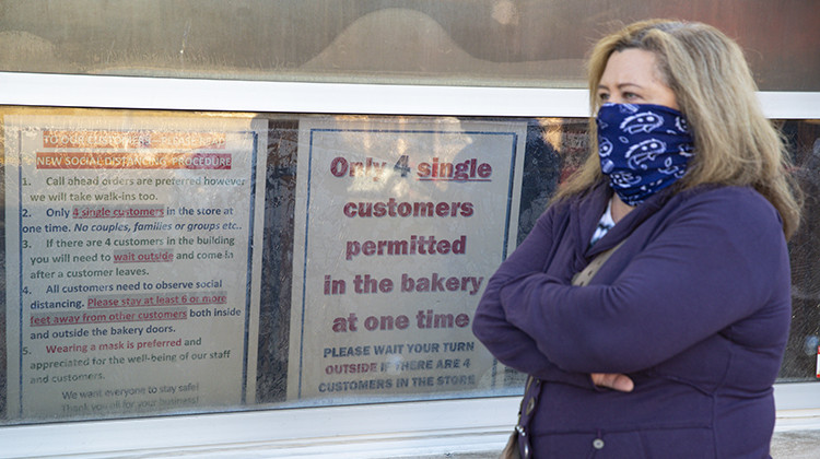 A masked customer waits in line next to a sign outlining the rules to enter at the Long's Bakery Shop in Indianapolis, Friday, May 1, 2020. The bakery reopened after closing it doors due to COVID-19. The bakery, considered an essential business, reopened as Indianapolis extended the city's stay-at-home order to May 15. Customers waited in the hour-long line to purchase the shop's signature yeast glazed donuts. - AP Photo/Michael Conroy