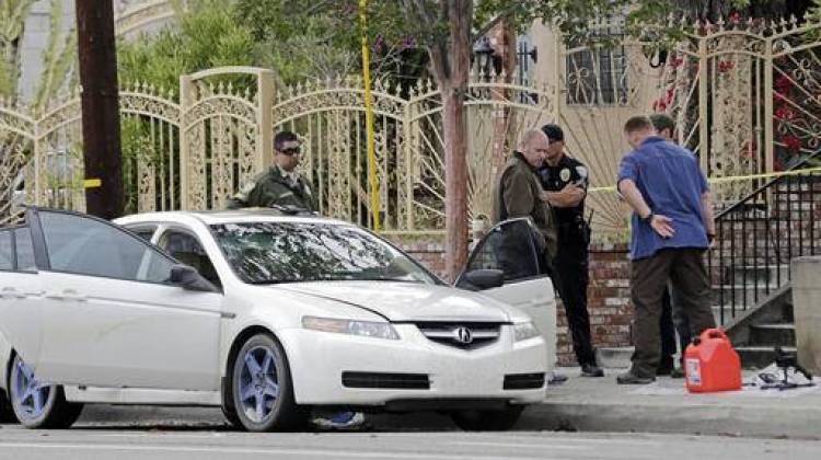 Investigators view items removed from a car, left, after a heavily armed man was arrested in Santa Monica, Calif., early Sunday, June 12, 2016. The man reportedly told police he was in the area for West Hollywood's huge gay pride parade. Authorities did not know of any connection between the gay nightclub shooting in Orlando, Fla., early Sunday and the Santa Monica arrest.  - AP photo/Reed Saxon