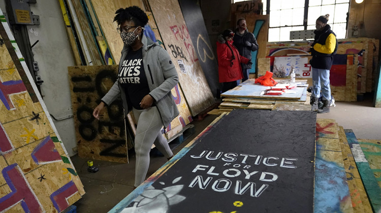 Leesa Kelly, left, walks past plywood mural boards as she and Kenda Zellner-Smith, background right, and volunteers meet at a warehouse, Saturday, Dec. 12, 2020, in Minneapolis to organize them. The two women formed the Save the Boards to Memorialize the Movement to preserve the painted expressions and pain born of outrage after the death of George Floyd at the hands of Minneapolis police in May.  - AP Photo/Jim Mone