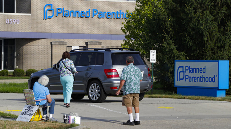 FILE - In this Aug. 16, 2019 file photo, abortion protesters attempt to handout literature as they stand in the driveway of a Planned Parenthood clinic in Indianapolis. - AP Photo/Michael Conroy