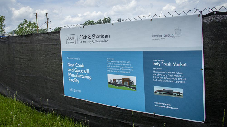 A sign on the fence surrounding the construction site promotes the Cook and Goodwill manufacturing facility and the Indy Fresh Market.  - FILE: Doug Jaggers/WFYI