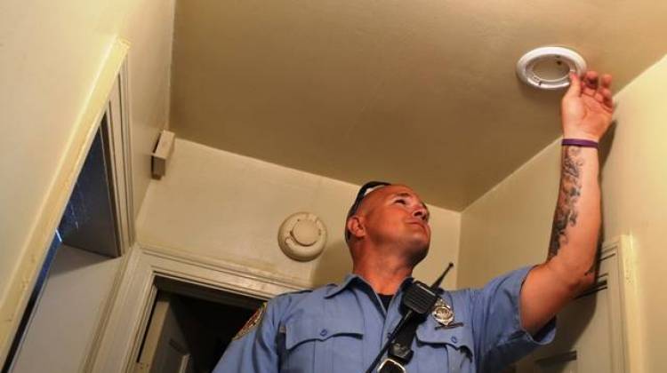 Indianapolis firefighter Derek Huff installs a smoke detector in a home on North Sherman Drive Tuesday. - Ryan Delaney/WFYI