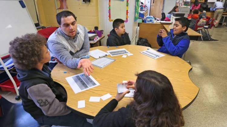 Fourth grade instructional aid Henry Velasquez works with students at Enlace Academy. More than half of the school's students are English learners. - Kelly Wilkinson / The Indianapolis Star