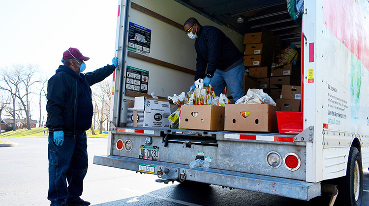 Church volunteers distribute free food out from a U-Haul truck in a parking lot.  - Justin Hicks/IPB News