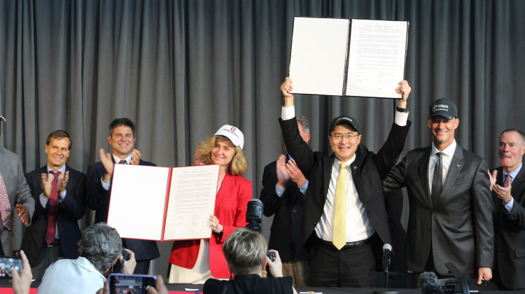 Purdue and Indiana University Presidents Mung Chiang and Pamela Whitten hold up the official agreement to dissolve IUPUI.  - (WBAA News/Ben Thorp)