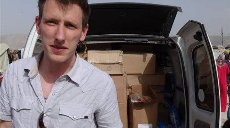 This undated photo provided by Kassig Family shows Peter Kassig standing in front of a truck filled with supplies for Syrian refugees. A video purportedly produced by militants in Syria released Friday, Oct. 3, 2014, shows Kassig, of Indianapolis, kneeling on the ground as a masked militant says he will be killed next. - Associated Press photo