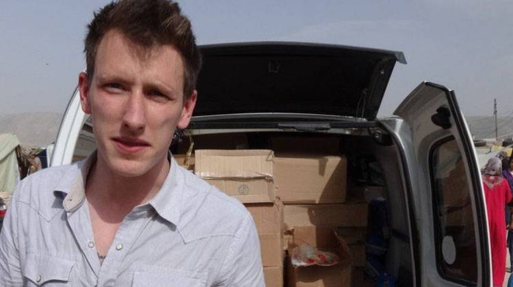 In this undated file photo provided by his family, Abdul-Rahman Kassig stands in front of a truck filled with supplies for Syrian refugees. - AP Photo/Courtesy Kassig Family, File