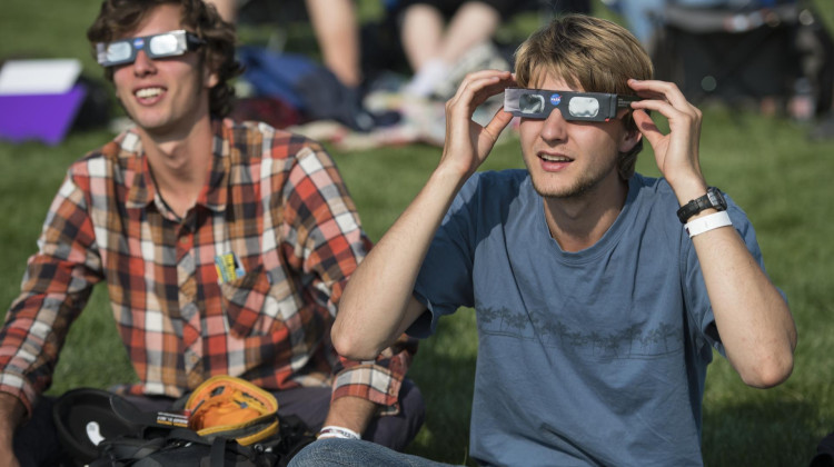 People are seen as they watch a total solar eclipse through protective glasses in Madras, Oregon on Monday, Aug. 21, 2017. - NASA / Aubrey Gemignani