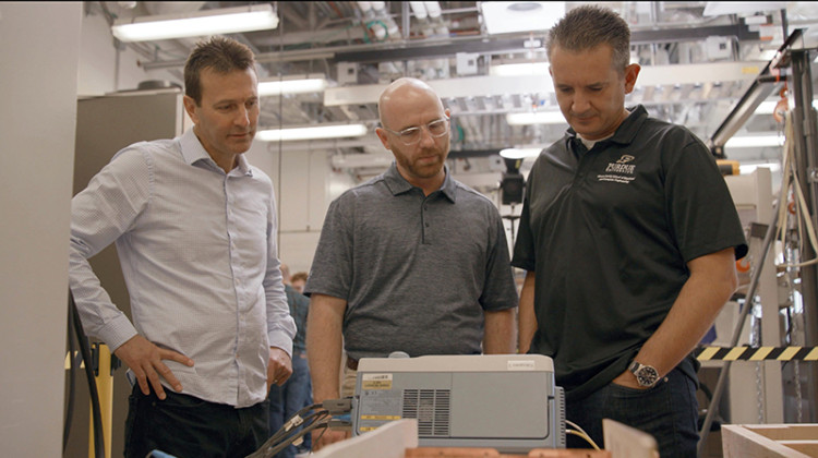 Aaron Brovont (middle) and other engineers seen in a lab surveying technology that can charge electric vehicles. - Courtesy of Purdue University