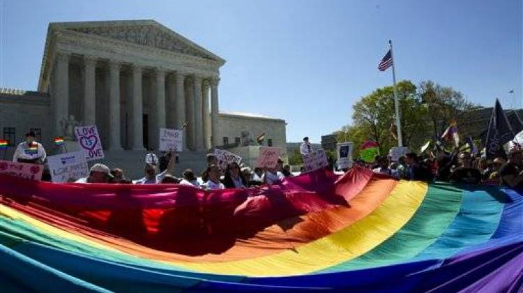 In this April 28, 2015, file photo, demonstrators stand in front of a rainbow flag of the Supreme Court in Washington, as the court was set to hear historic arguments in cases that could make same-sex marriage the law of the land.  - The Associated Press