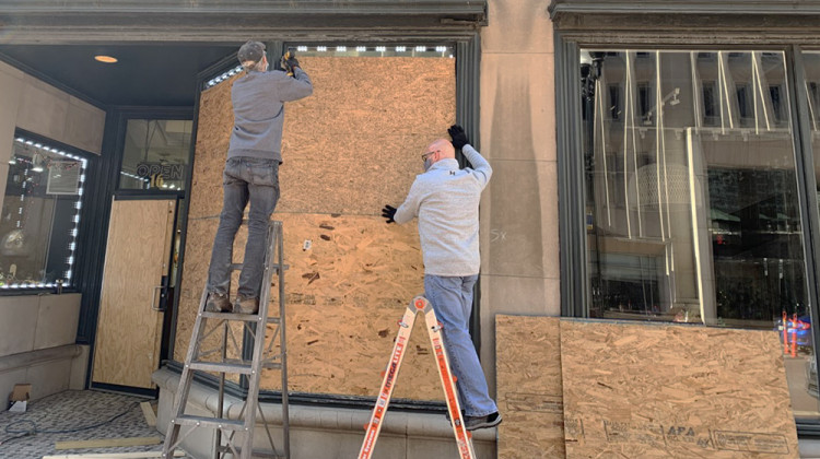 Workers install plywood over windows of the Windsor Jewelry store in downtown Indianapolis on Monday, Nov. 2. - Robert Moscato-Goodpaster/WFYI