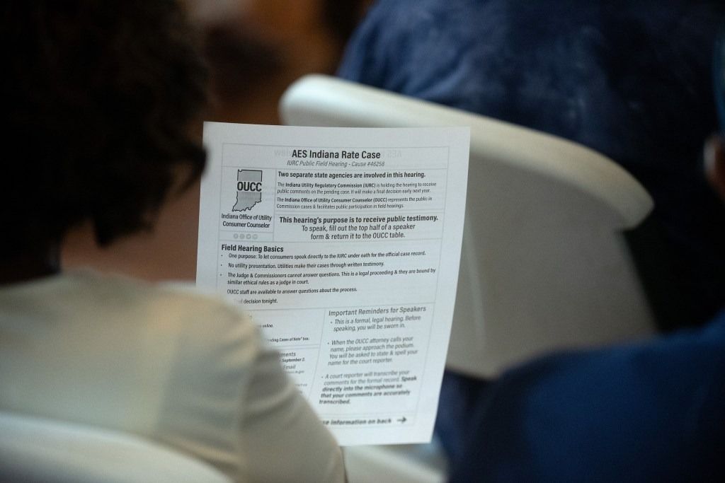 A person in the audience looks at an informational handout Aug. 21, 2025, during an Indiana Utility Regulatory Commission field hearing concerning AES utility rates, at Southeast Community Services in Indianapolis. 