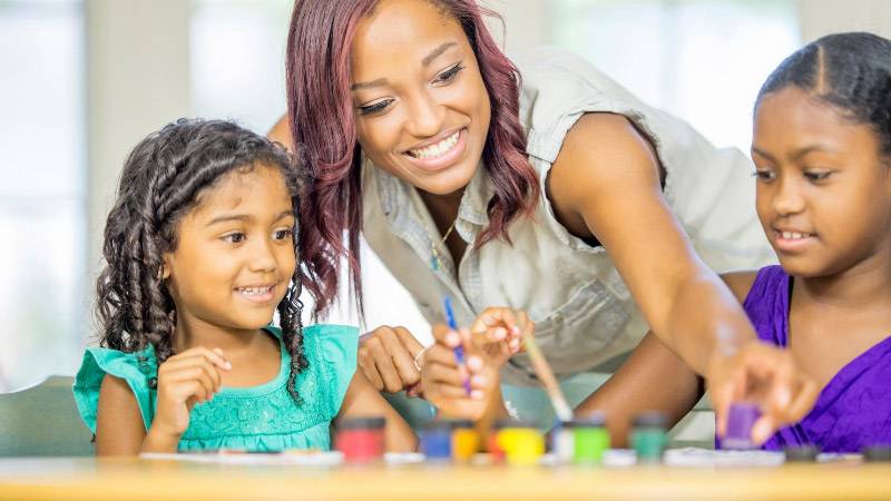 2 young girls and adult woman doing a learning activity