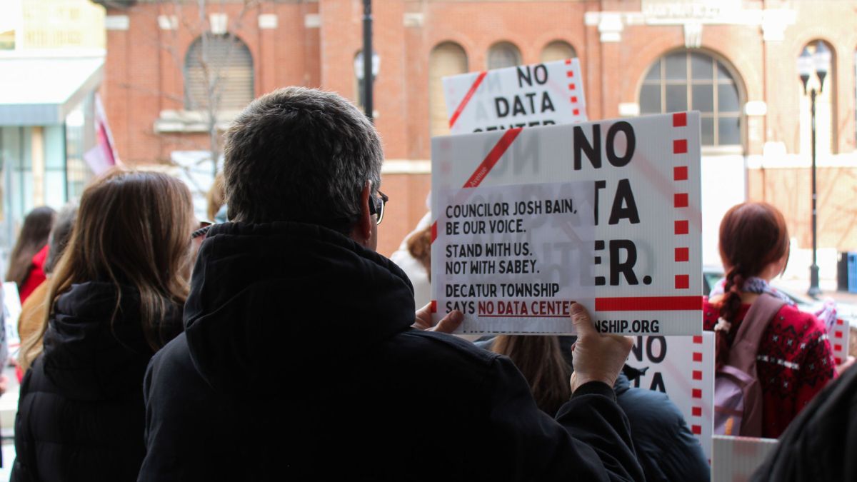 A protester holds a sign urging City-County Councilor Josh Bain, who represents the district where the data center would be built, to 'Stand with us. Not with Sabey.'