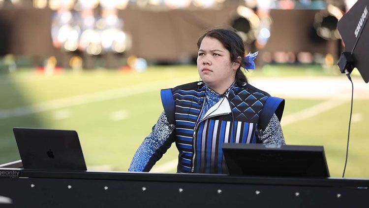 Jasmine plays the piano synthesizer during a marching band performance.