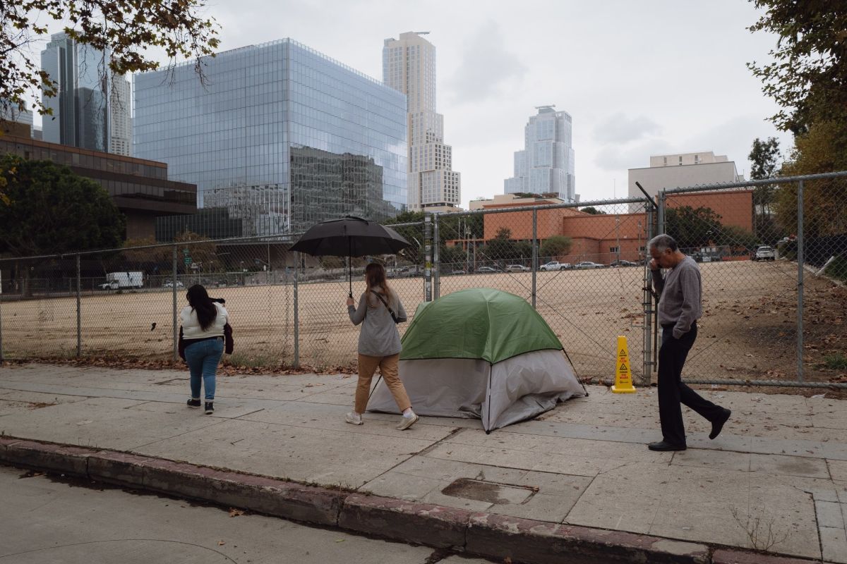 Jazmine Mapes holds her son as she walks along the sidewalk where she lived in a tent for three years while unhoused in downtown Los Angeles, California. November 17, 2025.