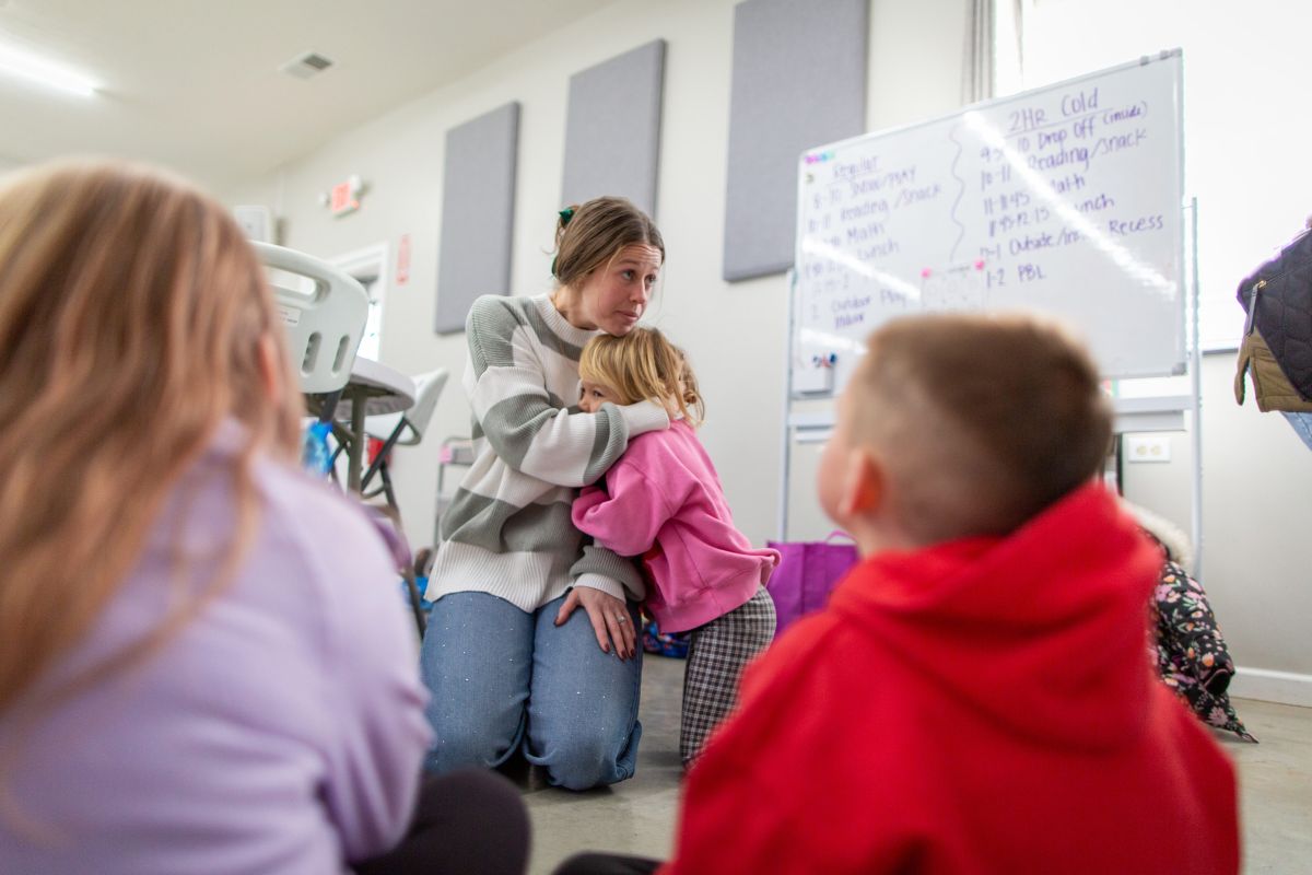 Teacher Emma Kersey is embraced by her daughter Baylor during lessons. Kersey says one of the benefits of teaching at this school is that her preschool-aged daughter is able to attend a year early. 