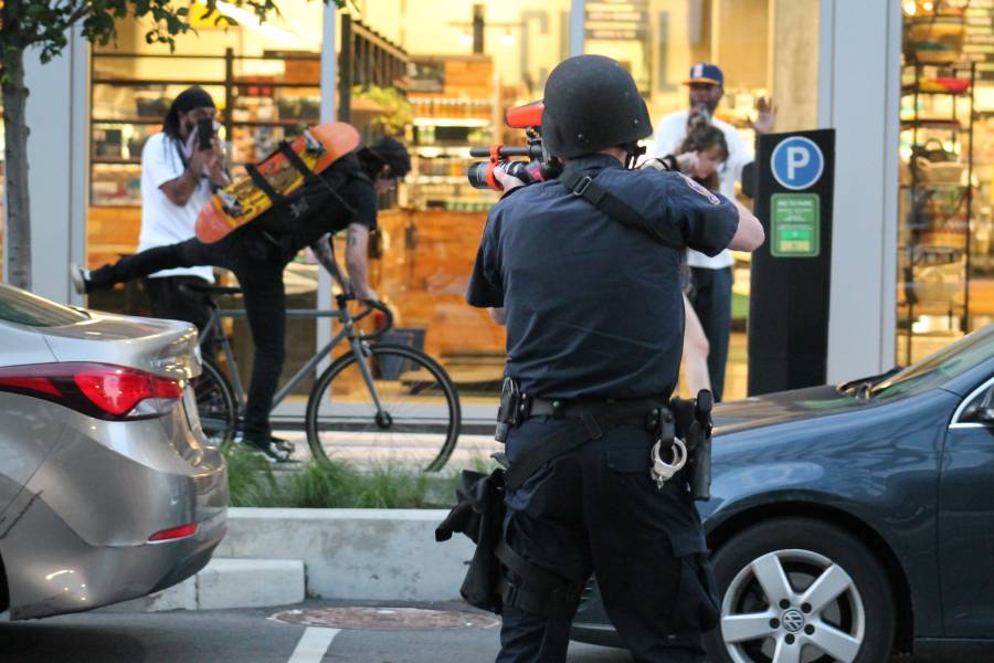 An IMPD officer begins shooting pepper spray pellets at protesters fleeing Market Street. Officers shot flares, tear gas canisters, pepper spray and pepper spray pellets to the gathered crowd. (Lauren Chapman/IPB News)