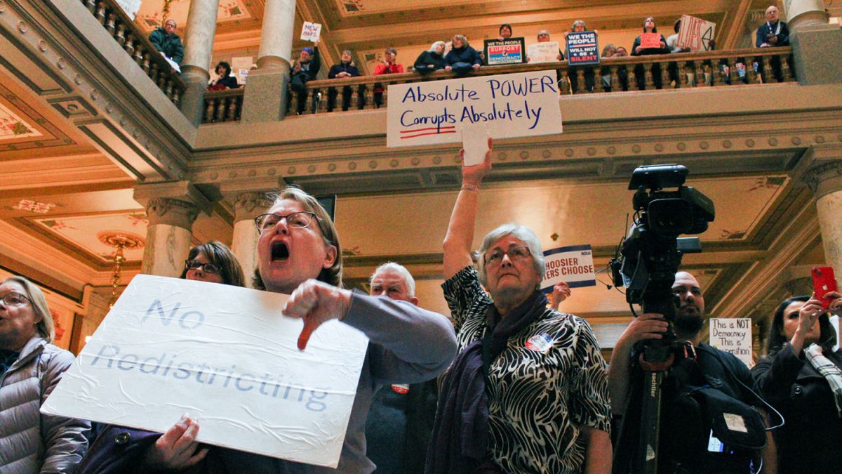 Protestors hold signs and shout against the push to redistrict at the Indiana Statehouse on Monday, Dec. 1, 2025 .