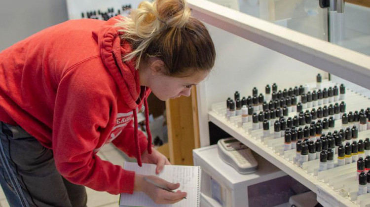 Faith White, an employee of Great Alternatives Vape Shop in suburban Des Moines, takes inventory of the store's vaping flavors. - Natalie Krebs/Side Effects Public Media