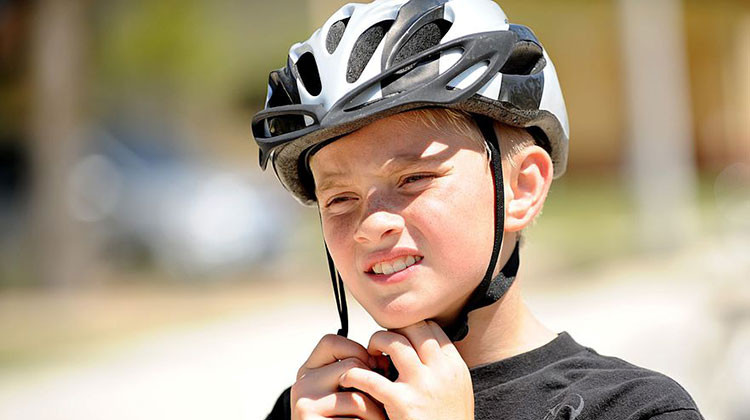 A boy secures his helmet during the Bicycle Safety Rodeo June 9, 2012, at Incirlik Air Base, Turkey. - Senior Airman Jarvie Wallace/United States Air Force