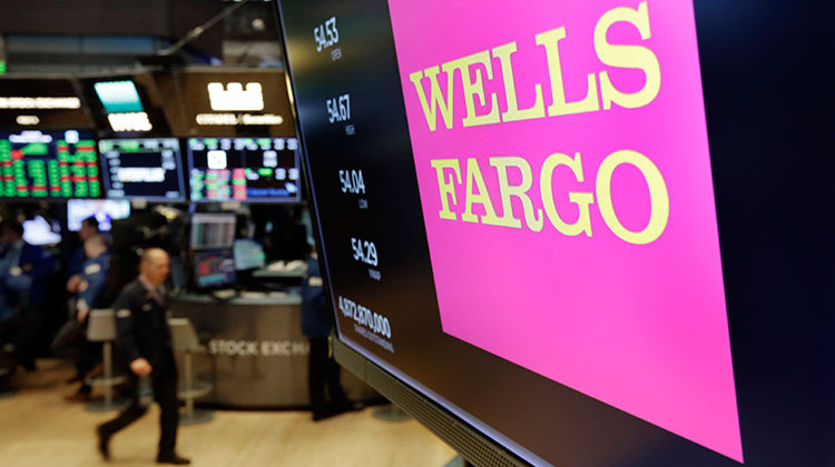 FILE - This May 17, 2018 file photo shows the Wells Fargo logo above a trading post on the floor of the New York Stock Exchange. Wells Fargo is selling more than 50 retail bank branches in Indiana, Michigan, Wisconsin and Ohio to a Flagstar Bancorp subsidiary. - AP Photo/Richard Drew, File