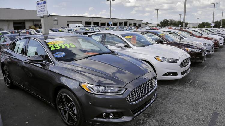 A car salesman works the telephone while searching through inventory at the certified used car lot at Brandon Ford in Brandon, Fla. - Chris O'Meara/AP