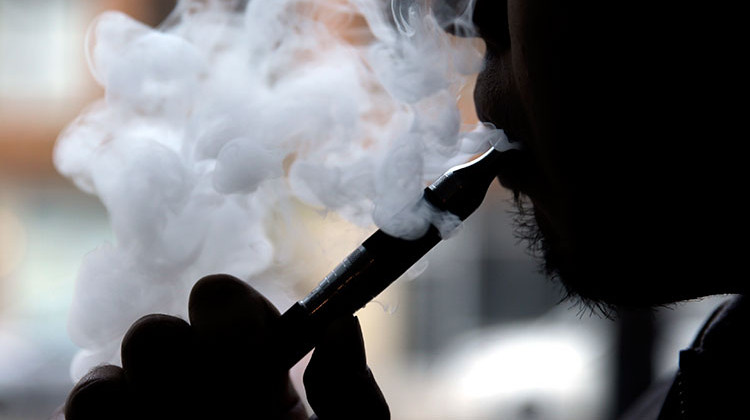 FILE - In this April 23, 2014 file photo, a man smokes an electronic cigarette. Columbus, Indiana is joining the list of communities around the state banning the use of electronic cigarettes in most public places. - AP Photo/Nam Y. Huh, File