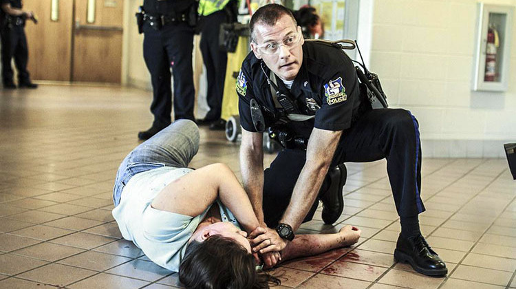 A change in Illinois law means K-12 students must participate in an active shooter drill within the first 90 days of the school year. In this photo, a Paducah Police officer aids a "victim" during an active-shooter mock exercise at West Kentucky Community and Technical College. - “Aid to Injury” by MAMC Photography/CC-BY-NC-SA-2.0