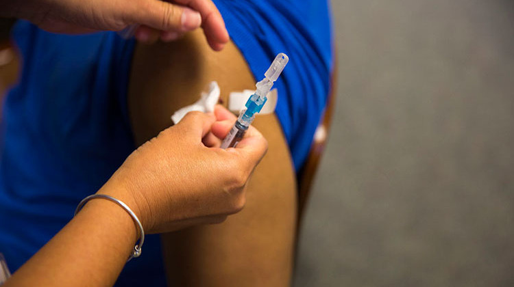 A healthcare professional puts a band aid over the site of an injection after providing a flu vaccine to a patient. - Cpl. Jackeline Perez Rivera/United States Marine Corps