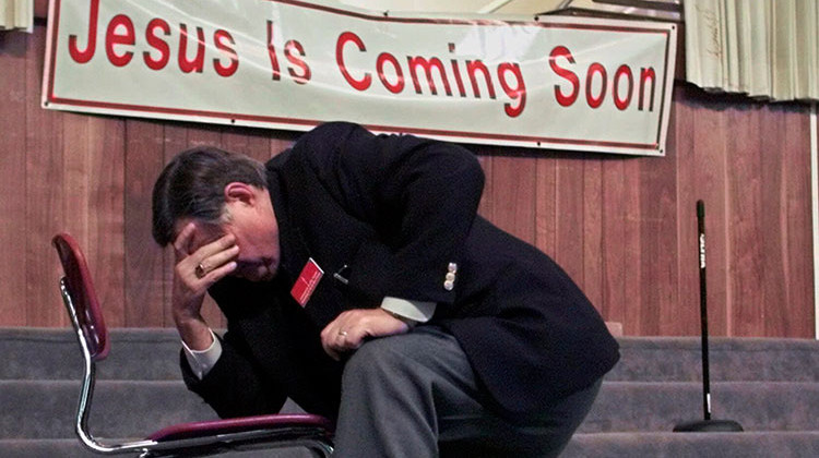 FILE- In this Nov. 14, 2000 file photo, Rev. Greg J. Dixon prays on his knees along with other supporters and members of the Indianapolis Baptist Temple, In Indianapolis, Ind. Dixon, founder of the Indianapolis Baptist Temple that federal marshals seized in a tax dispute, has died. He was 87.  - AP Photo/Michael Conroy File