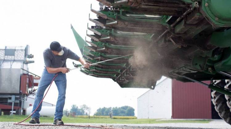 A farmer cleans a combine, one of many pieces of farm equipment that generates trackable data. - United Soybean Board
