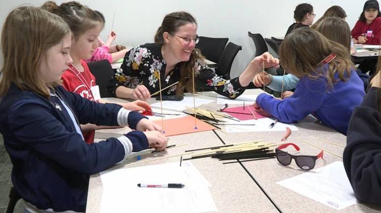 The first activity of the day was for the girls to build a structure out of clay and straws to withstand an earthquake, simulated by shaking a piece of cardboard on top of tennis balls. - Jeanie Lindsay/IPB News