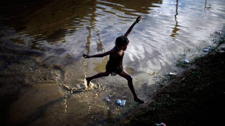 A little girl jumps across a flooded field containing the sewage runoff from the Mais Gate Camp after heavy rains in Port-au-Prince in 2010.
