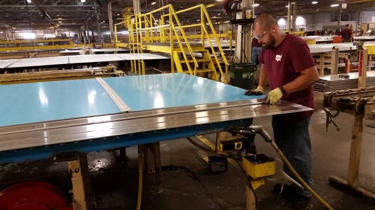 A Wabash National worker slides a partially finished trailer wall onto his station for riveting. - Annie Ropeik/Indiana Public Broadcasting