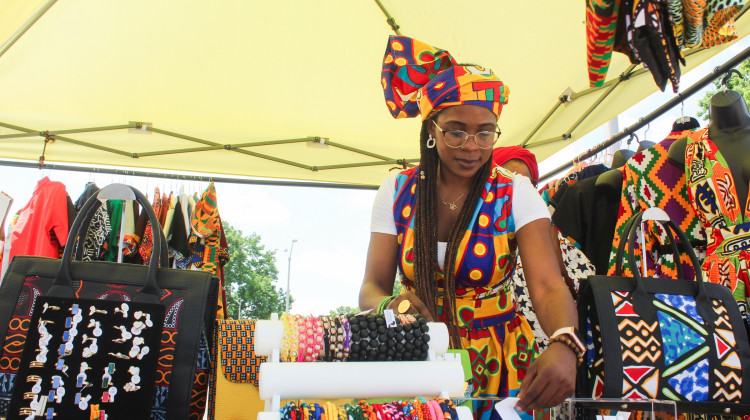 Laila Saahir, an Indianapolis resident, arranges her items as a vendor at the Indy Juneteenth event on Saturday, June 21. Saahir, who is originally from Cameroon, owns Afrikan Authentix, an online clothing boutique that sells handmade African clothing and accessories. - Farrah Anderson/WFYI