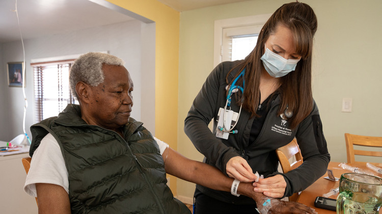 Gabriel Kibuyu (left) receives treatment for a severe urinary tract infection from UMass Memorial Medical Center nurse Danae Stand (right) at his home in Worcester, Massachusetts, on March 6, 2023. - Lisa Abitbol for Tradeoffs