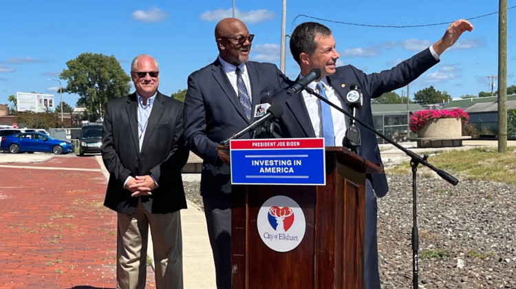 Pete Buttigieg, former South Bend mayor and current U.S. transportation secretary, laughs and waves at a passing train Wednesday as its horn temporarily drowns out their press conference at the Elkhart rail depot. With him are Elkhart Mayor Rod Roberson, middle, and Tony Gianesi, interim transportation director for Elkhart Community Schools. - Jeff Parrott/WVPE