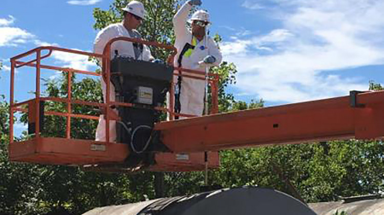 EPA contractors sample an above ground storage tank. - Courtesy of the EPA