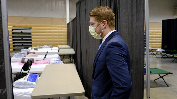 Brett Peppin, director of environmental health with Boone County Health Department, looks beds set-up in a building at the Boone County 4-H Fairgrounds to handle COVID-19 patients, Monday, April 6, 2020, in Lebanon, Ind. The new coronavirus causes mild or moderate symptoms for most people, but for some, especially older adults and people with existing health problems, it can cause more severe illness or death. - AP Photo/Darron Cummings
