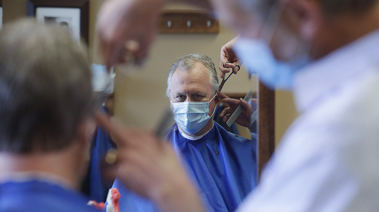 Geoff Brown gets a haircut from Mike Nell at the Boone Village Barber Shop, Monday, May 11, 2020, in Zionsville, Ind. Barber shops have been closed to prevent the spread of the coronavirus and were allowed to open Monday by appointment and following social distancing guidelines. - AP Photo/Darron Cummings