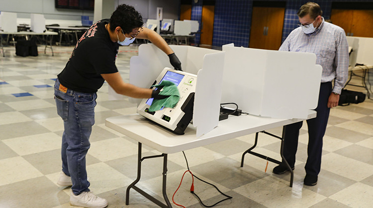 Joshua Lindl sanitizes a voting match as a voter casts his ballot in the Indiana primary in Indianapolis, Tuesday, June 2, 2020. Coronavirus concerns prompted officials to delay the primary from its original May 5 date. Nearly 550,000 voters requested mail-in ballots, more than 10 times the number of those ballots cast during the 2016 primary.  - AP Photo/Michael Conroy