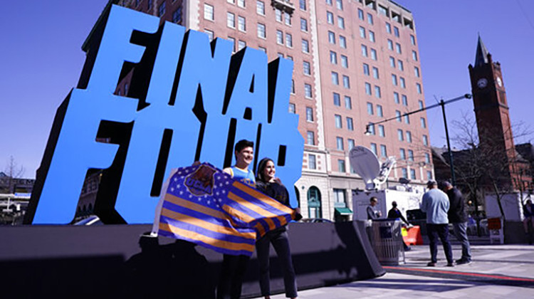 Fans pose with a Final Four logo before a college basketball game during the Final Four round of the NCAA tournament at Lucas Oil Stadium in Indianapolis, Saturday, April 3, 2021.  - AP Photo/AJ Mast