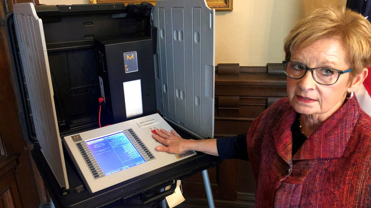 FILE - Then-Indiana Secretary of State Connie Lawson demonstrates an upgraded voting machine at the Indiana Statehouse office in Indianapolis on Sept. 25, 2019. A proposal for improving Indiana’s election security by adding small printers to thousands of electronic touch-screen voting machines is being criticized by voting rights groups as relying on ineffective and outdated technology. An Indiana Senate committee is scheduled to consider a bill Monday, Feb. 14, 2022, that includes moving  - AP Photo/Tom Davies File