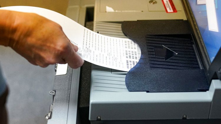 A voter inserts her ballot into a scanner as she votes in the primary election in Indianapolis, Tuesday, May 3, 2022.  - AP Photo/Michael Conroy
